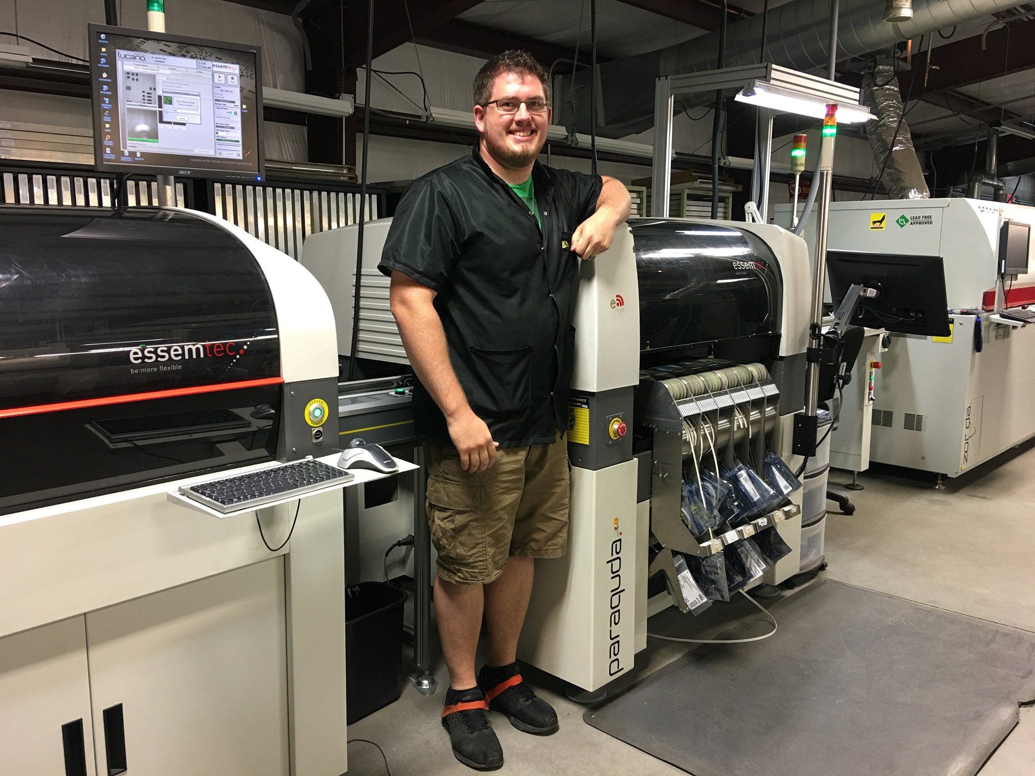EMS team member next to an SMT pick-and-place machine on the PCB assembly line