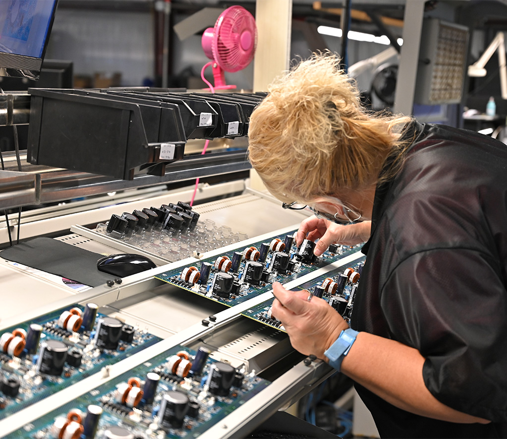Technician hand-assembling through-hole components on a PCB